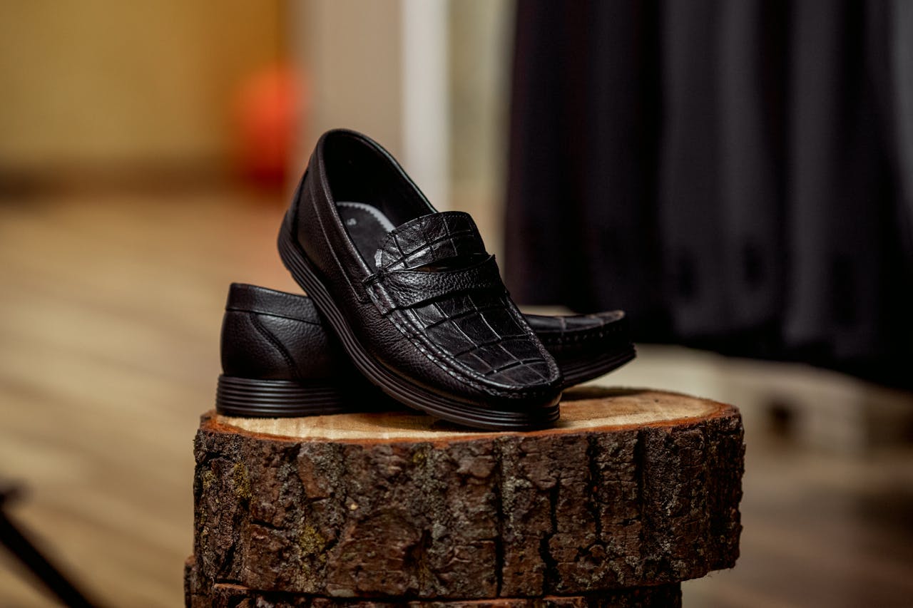 about-img-01 Stylish black loafers displayed on wood, highlighting detailed craftsmanship.